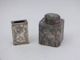 two small silver objects are sitting on a white surface