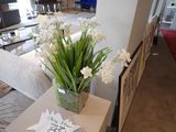 un vase avec des fleurs blanches posé sur une table dans un salon