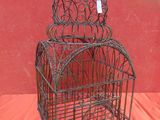 une vieille cage à oiseaux avec une étiquette, posée sur un tissu rouge
