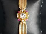 a close up of a gold and pink bracelet on a black pillow