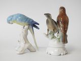 two figurines of birds that are sitting on a branch
