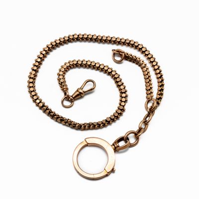 a close up of a gold chain with a ring on a white background