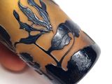 a hand holding a vase with a black and gold design