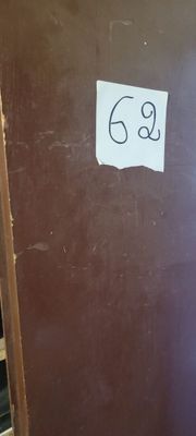 une porte marron sur laquelle figure un numéro, dans une pièce