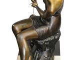 bronze statue of a man sitting on a rock with a glass of wine in his hand