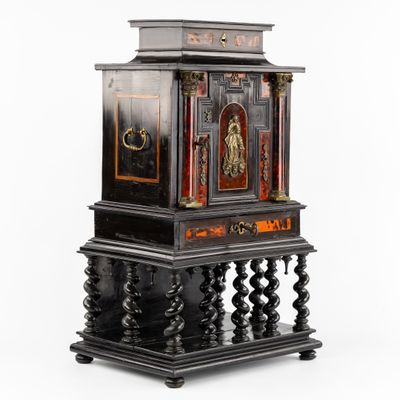 une horloge noire et dorée posée sur un socle, sur fond blanc