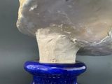 a blue vase that has a white shell on top of it