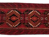 a close up of a red and black rug on a white surface