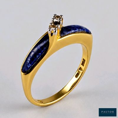un gros plan d'une bague en or sertie d'une pierre bleue et d'un diamant