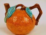 une théière en forme d'orange ornée d'une feuille verte