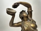 bronze statue of a woman holding a bowl with grapes in her hand