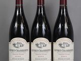three bottles of red wine are lined up on a table