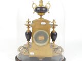 a gold clock under a glass dome on a table