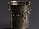 a silver cup on a black surface with a black background