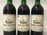 trois bouteilles de vin rouge posées l'une à côté de l'autre sur une surface blanche