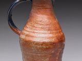 a brown vase with a blue handle sitting on a table