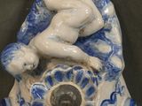 a blue and white porcelain sculpture of a woman on a clock