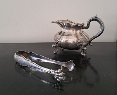 un pichet en argent et une paire de pinces posés sur une table
