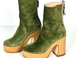 paire de bottes en daim vert à talon en bois sur fond blanc