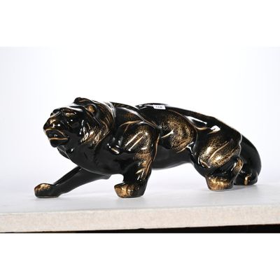 une statue de chien noire et dorée posée sur une surface blanche