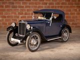 a vintage blue car parked in front of a brick wall