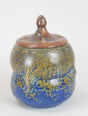 a blue and brown jar with a lid on a white surface