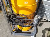 a yellow barrel sitting on top of a cart next to a hose