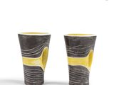 pair of yellow and black vases on a white surface
