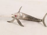 a silver fish with red eyes on a white surface