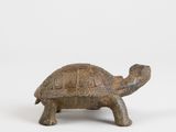 an old wooden turtle figurine sitting on a white surface