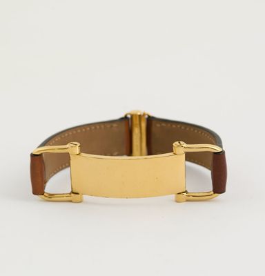 un gros plan d'une montre plaquée or montée sur un bracelet en cuir marron