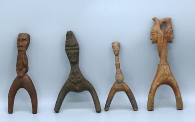 trois figurines en bois assises les unes à côté des autres sur une surface blanche