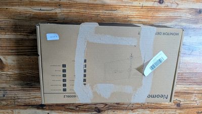 une boîte en carton posée sur une table en bois, sur laquelle est collé un autocollant