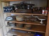 many plates and pans on the shelves in the kitchen