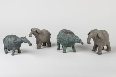 three small elephant figurines are standing next to each other on a white surface