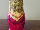 a red and gold matry doll sitting on a wooden table