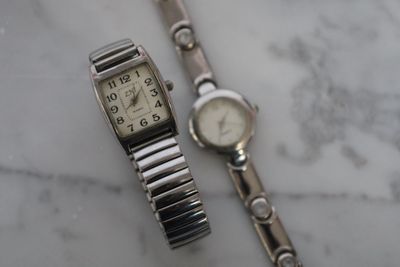 une montre en argent et un bracelet en argent posés sur une table en marbre