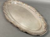 an oval silver tray with a decorative design on the edge