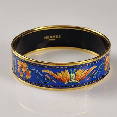 blue and gold bangle with flowers and leaves on a white surface