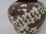 a brown and white vase with a lid on a table