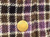 a close up of a button on a purple and black checkered jacket