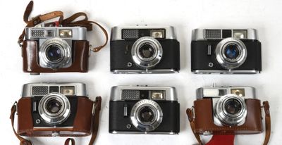 quatre appareils photo sont alignés sur une surface blanche, avec une lanière marron