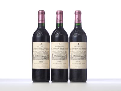 three bottles of red wine are lined up on a table