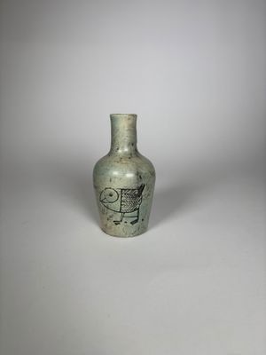 un petit vase vert orné d'une image d'oiseau
