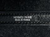 the label of a black leather bag with a white stitching