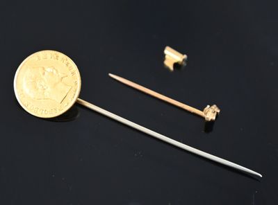 a gold coin and a small metal pin on a black surface