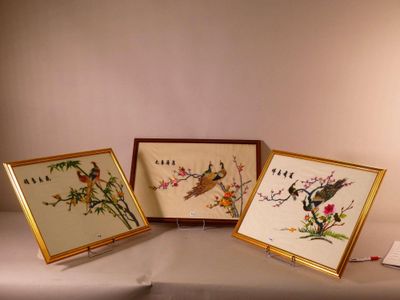 trois photos encadrées représentant des oiseaux et des fleurs sont posées sur une table
