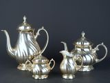 three pieces of silver tea and coffee set on a table