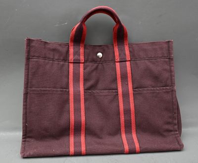 un sac marron orné de rayures rouges, posé sur une surface grise