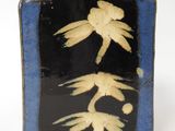 a black and blue vase with a yellow flower on it